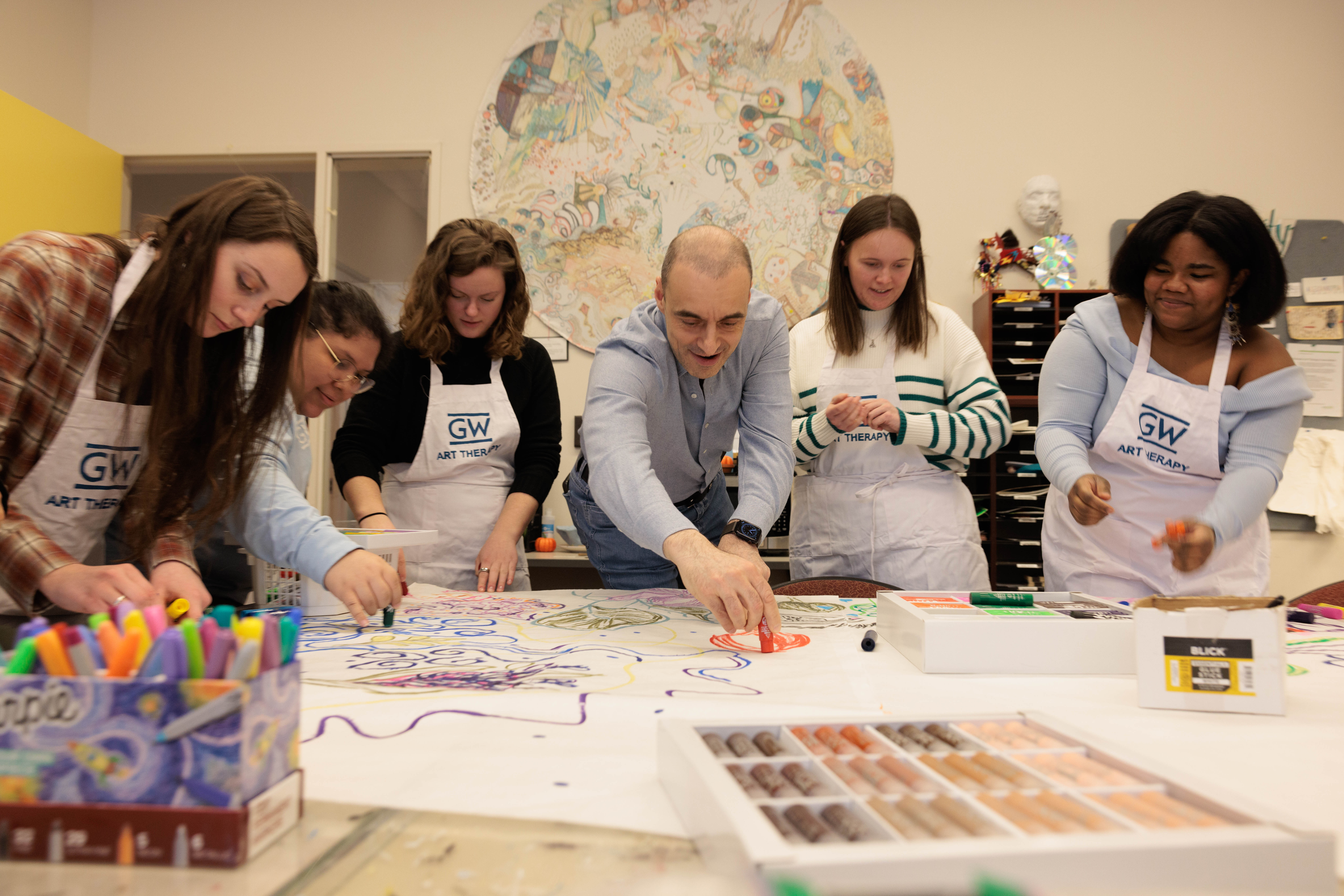 Ulvi Kasimov working on an art project with GW students at a shared table (Photos: William Atkins/GW Today)