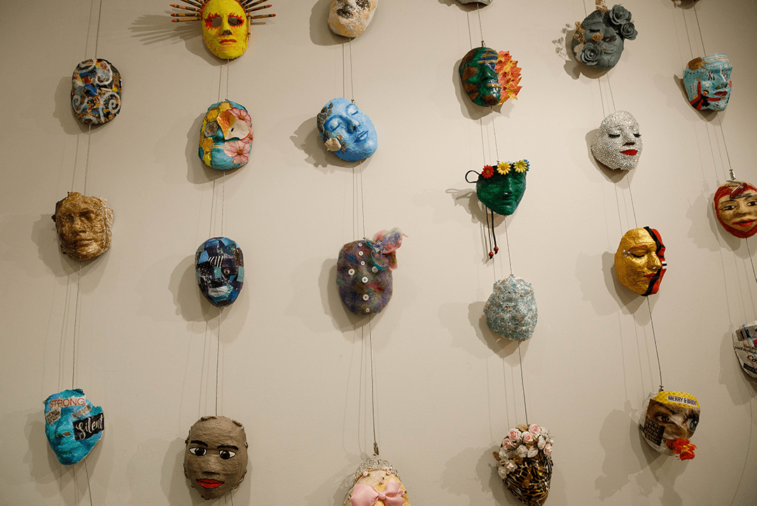 a wall full of hanging masks of different colors and designs