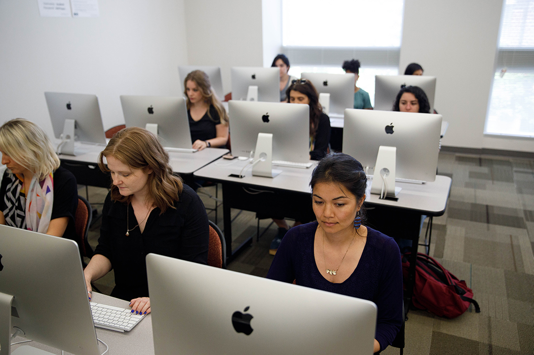 3 rows of students working on iMacs in a computer lab