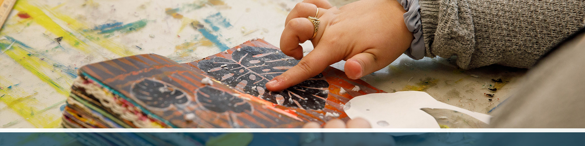 A student smooths down art in a sketchbook.